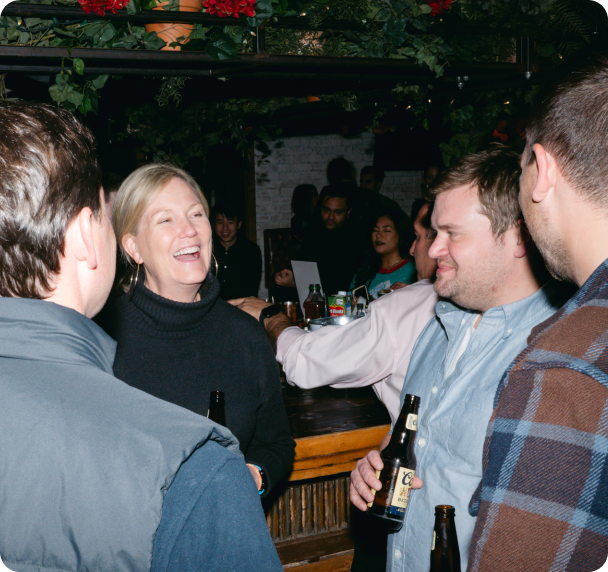 OneVest colleagues enjoying a social gathering at a bar, with a woman laughing in conversation